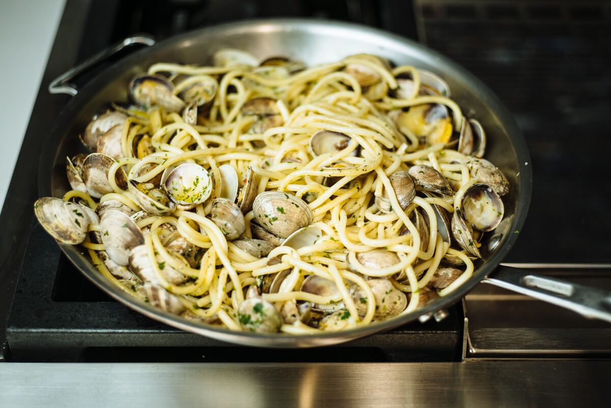 Cooking pasta with manila clams in a skillet for simple italian pasta and clams recipe from The Taste Edit