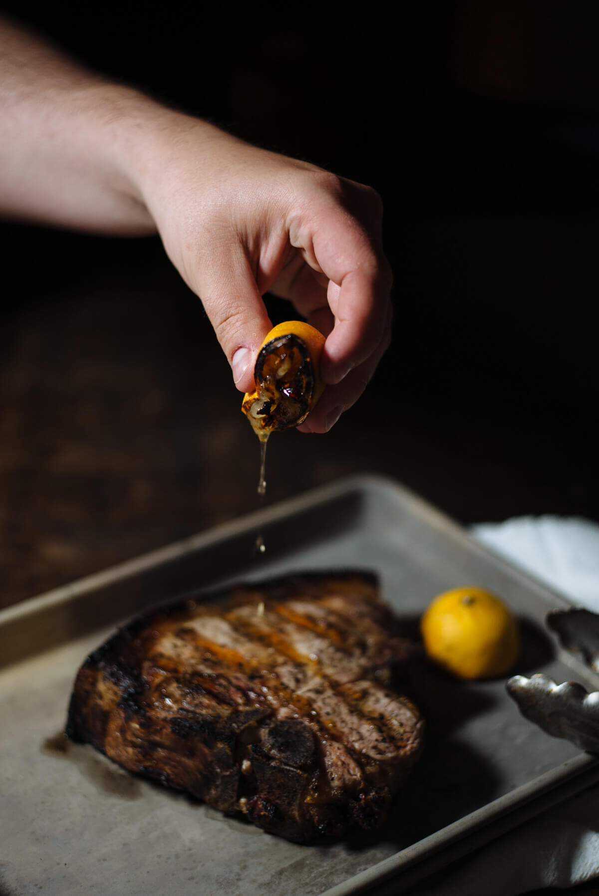 Squeezing a grilled lemon over a grilled pork chop