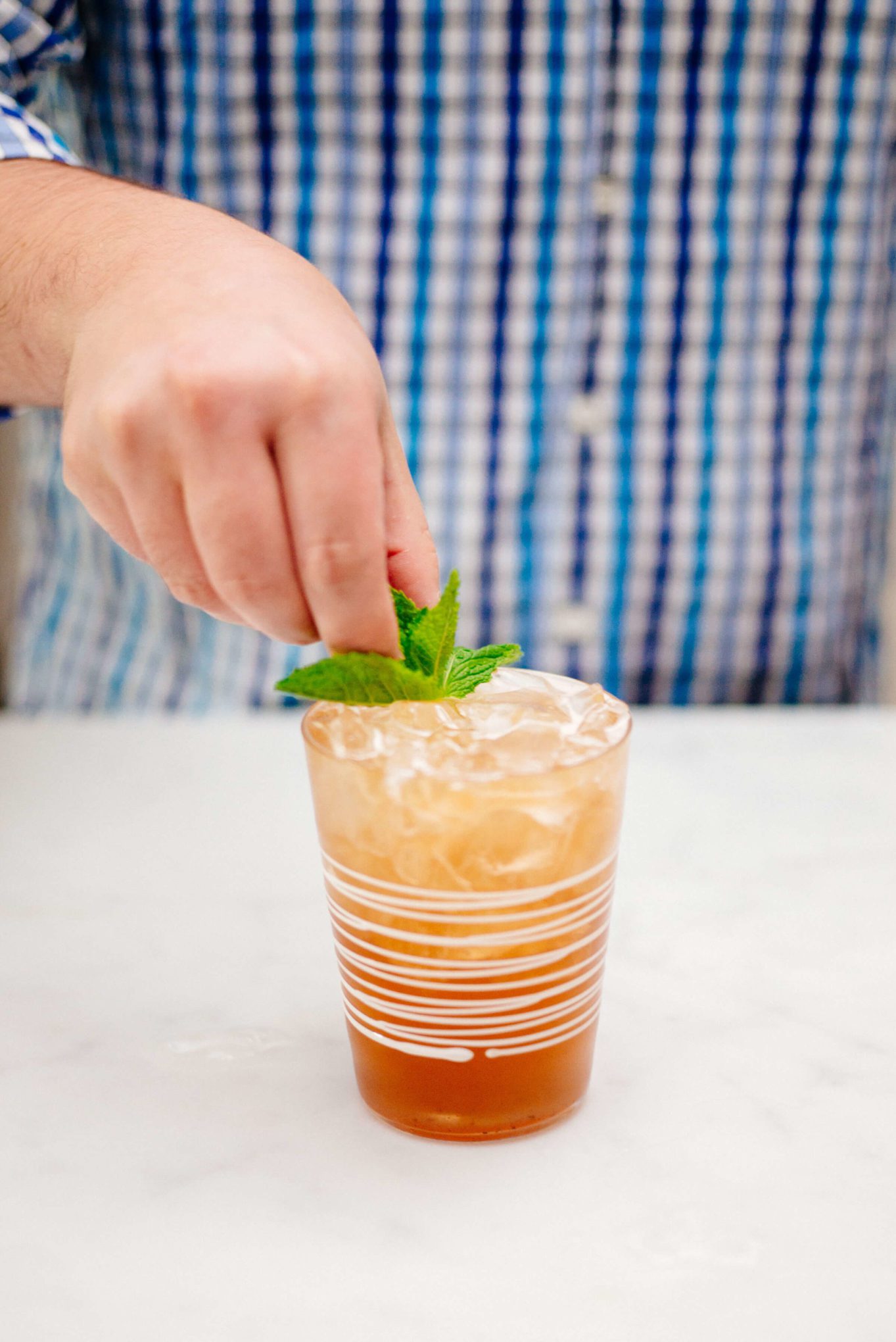 The Taste Edit is garnishing a jack and ginger cocktail with pomegranate ginger ale with a sprig of mint