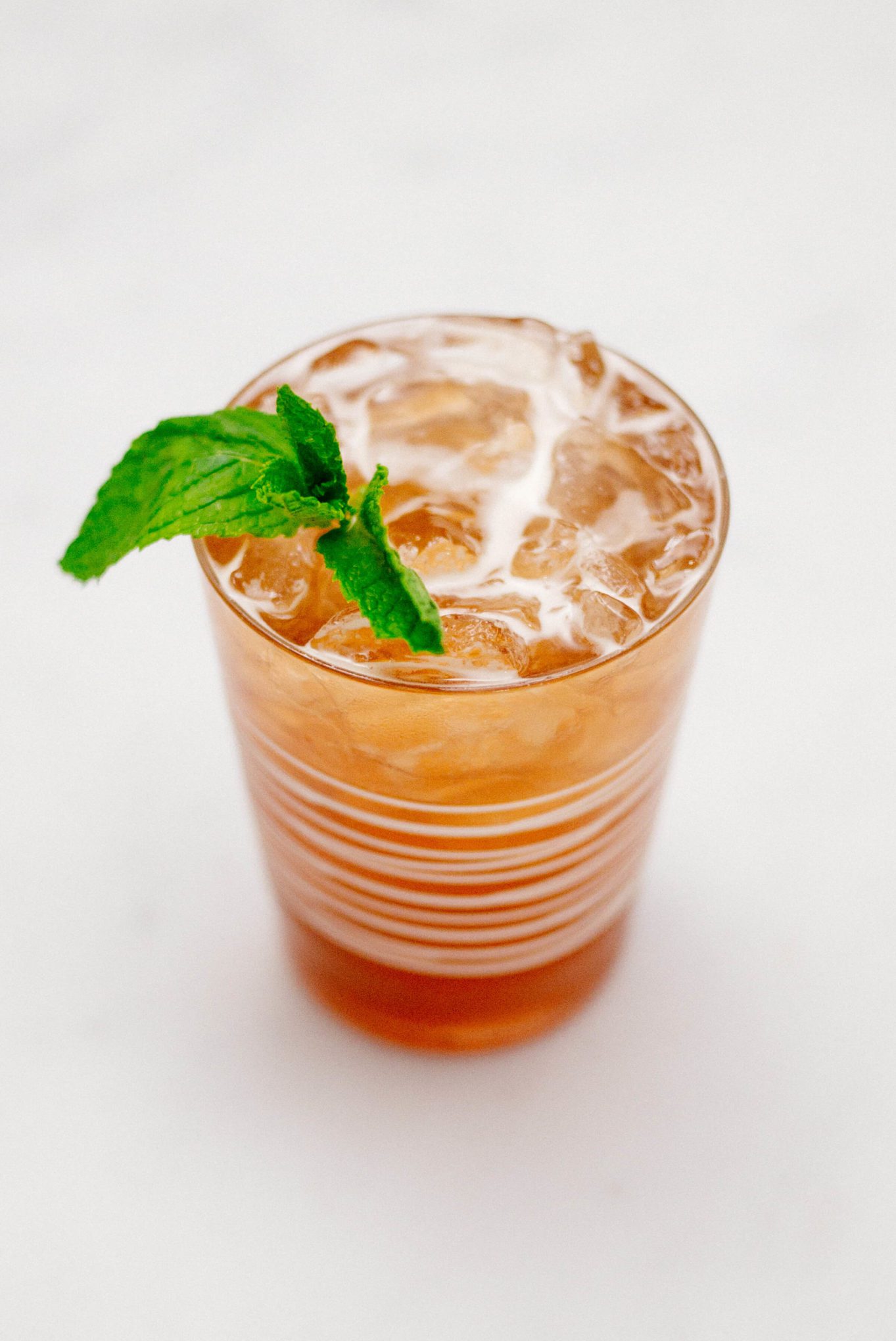 The Taste Edit is garnishing a jack and ginger cocktail with pomegranate ginger ale, bourbon, and mint