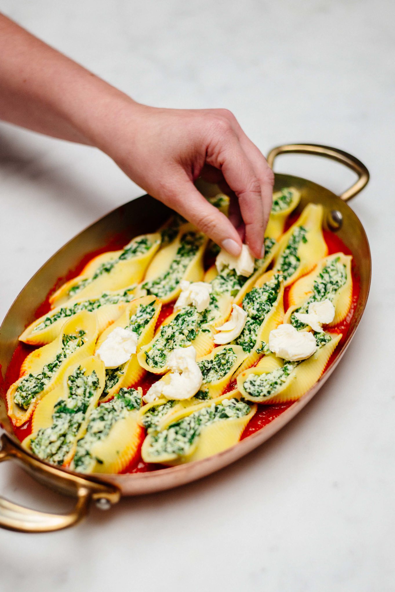 The Taste Edit placing mozzarella on top of baked stuffed shells
