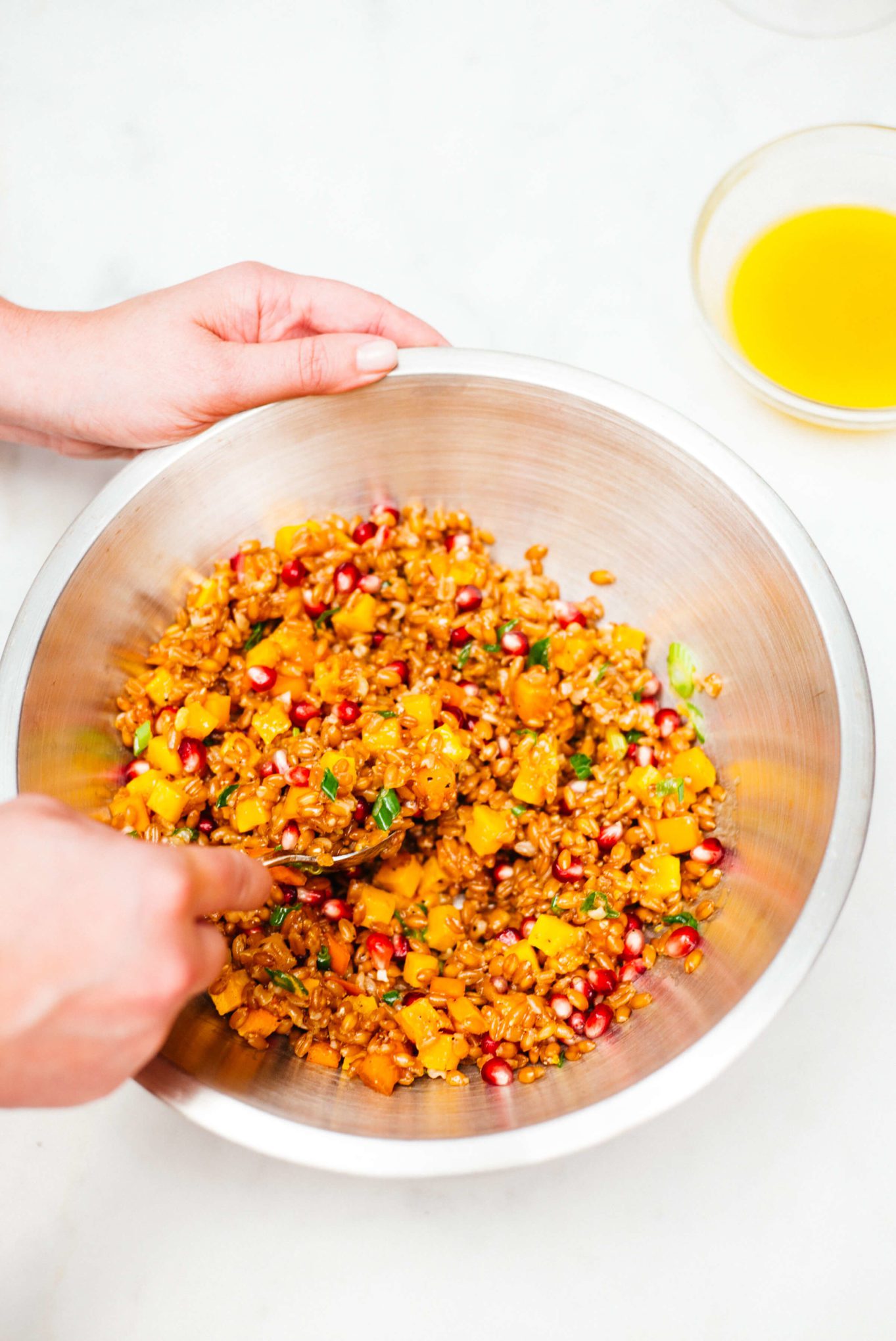 Stirring this autumn farro salad to distribute the dressing