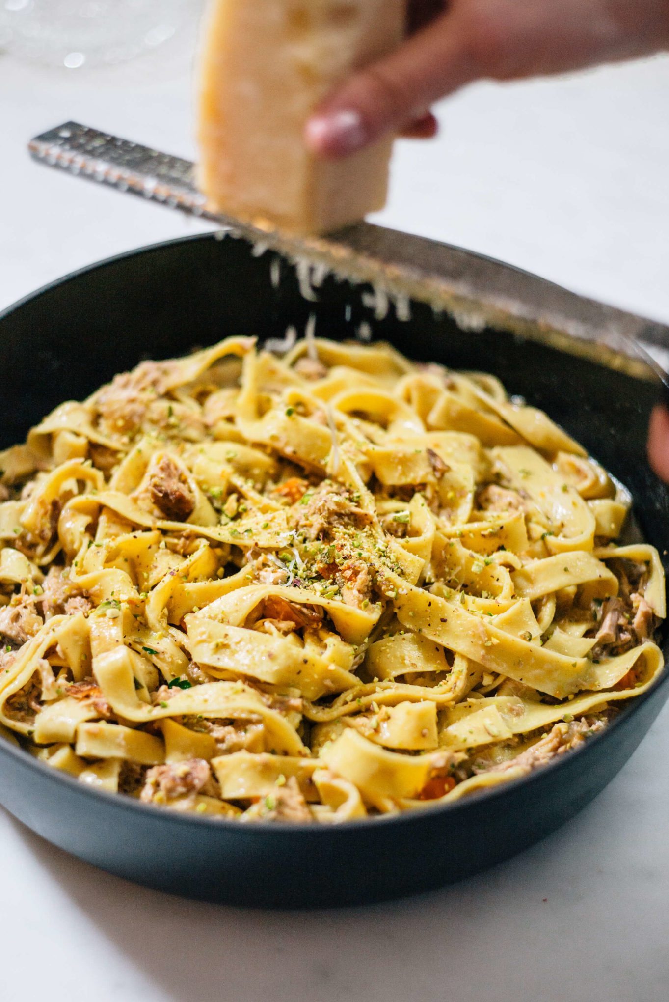 Topping Guinea Hen Winter Pasta with parmesan cheese via The Taste Edit - chicken, carrots, pistachios