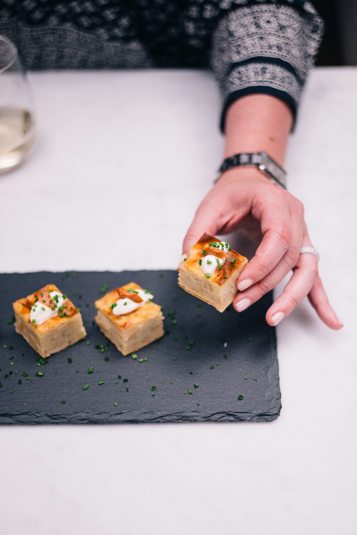 This simple and easy appetizer is Maria Sinskey's Potato Onion Torta topped with smoked salmon, chives, and sour cream made by The Taste Edit