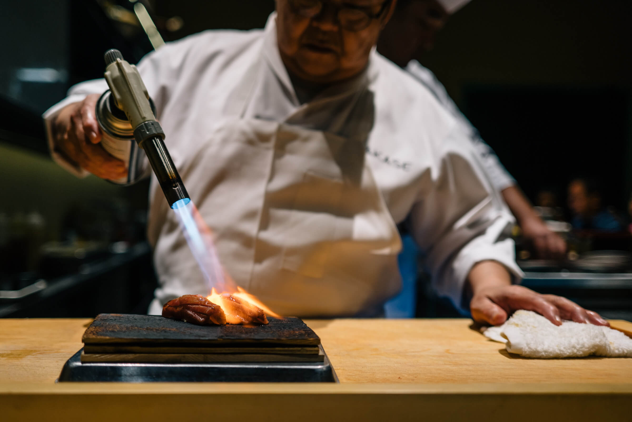 Chef searing wagyu beef with a torch at San Francisco's Omakase restaurant, The Taste Edit