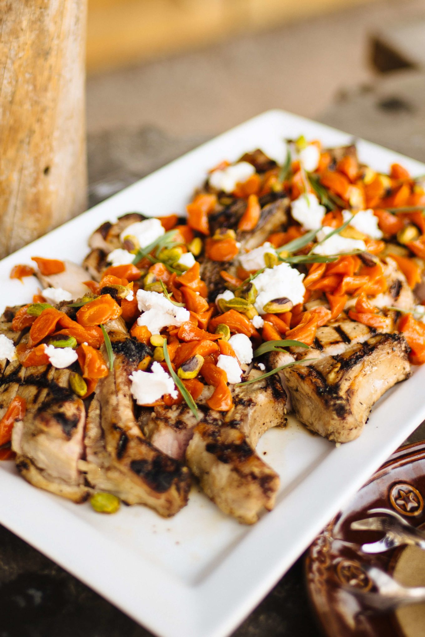 Delicious Maple-glazed carrots and chèvre with truffle-salted pistachios served on top of Maple Brined Pork Chops at The Resort at Paw's Up Cookbook Live Chuck Wagon Dinner, The Taste Edit