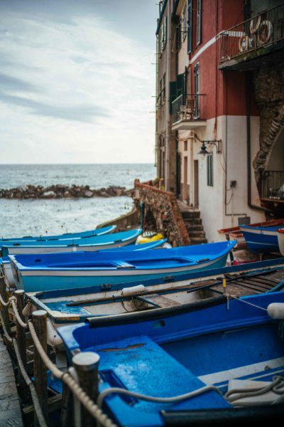 Scenes from riomaggiore in Cinque Terre with boats lined up for tourists to cruise the coast of the Mediterranean Sea.
