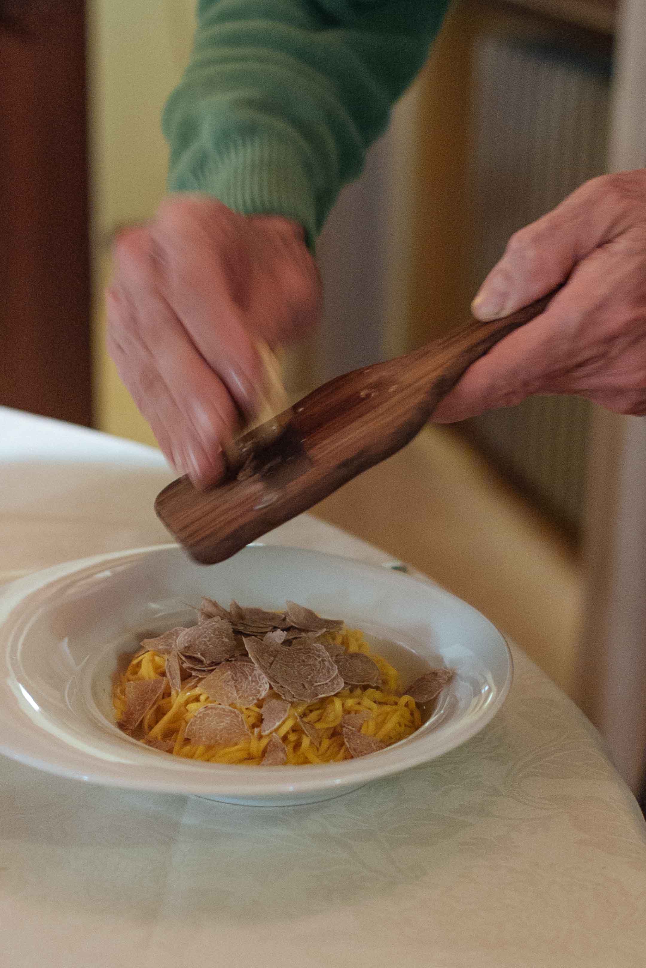 Close-up of hands shaving truffle over a plate of pasta at Restaurant Tra Arte E Querce in Monchiero owned by an award winning truffle hunter