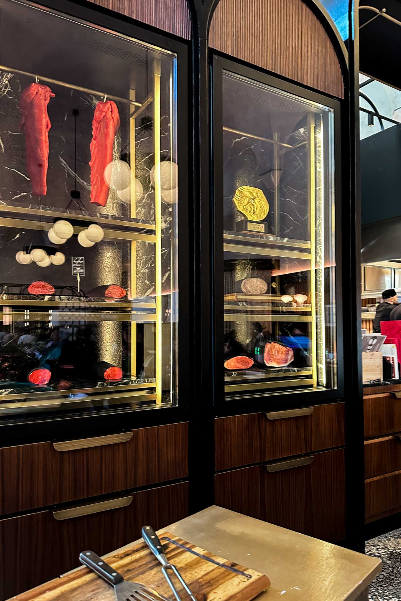 Display cases at Beefbar Milan showcasing tantalizing cuts of beef wrapped in black cloth.