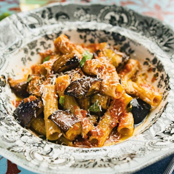 Delicious Sicilian Pasta alla Norma with fried eggplant and grated cheese on an ornate plate, ready to be served.