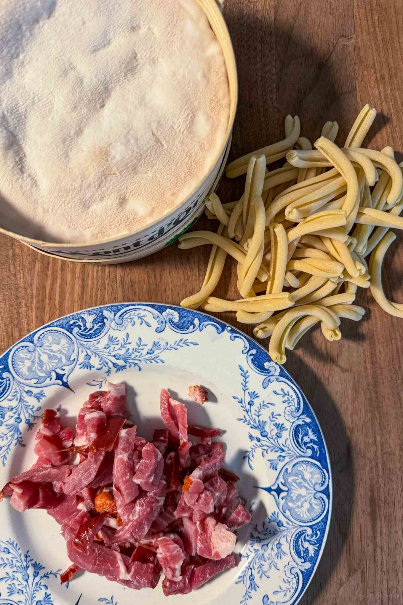 ingredients for a mont d'or cheese with pasta recipe including cheese, pasta, and bacon