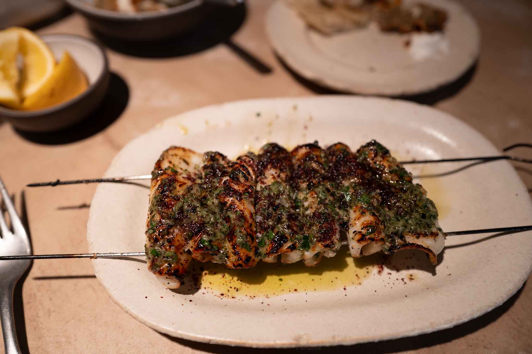 Oma London restaurant in borough market serves fresh seafood from the grill like these skewers of calamari and lemon wedges