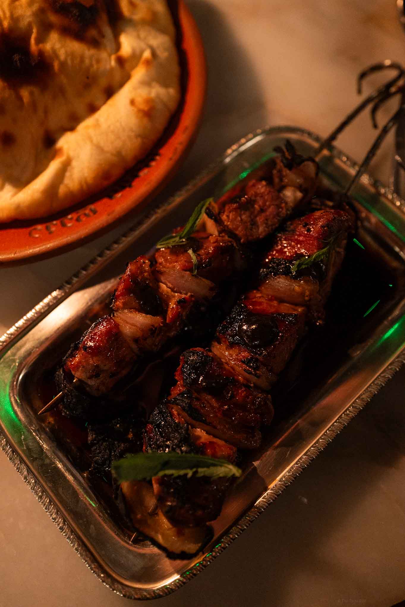 Juicy grilled beef skewers with green peppers on a glass dish.