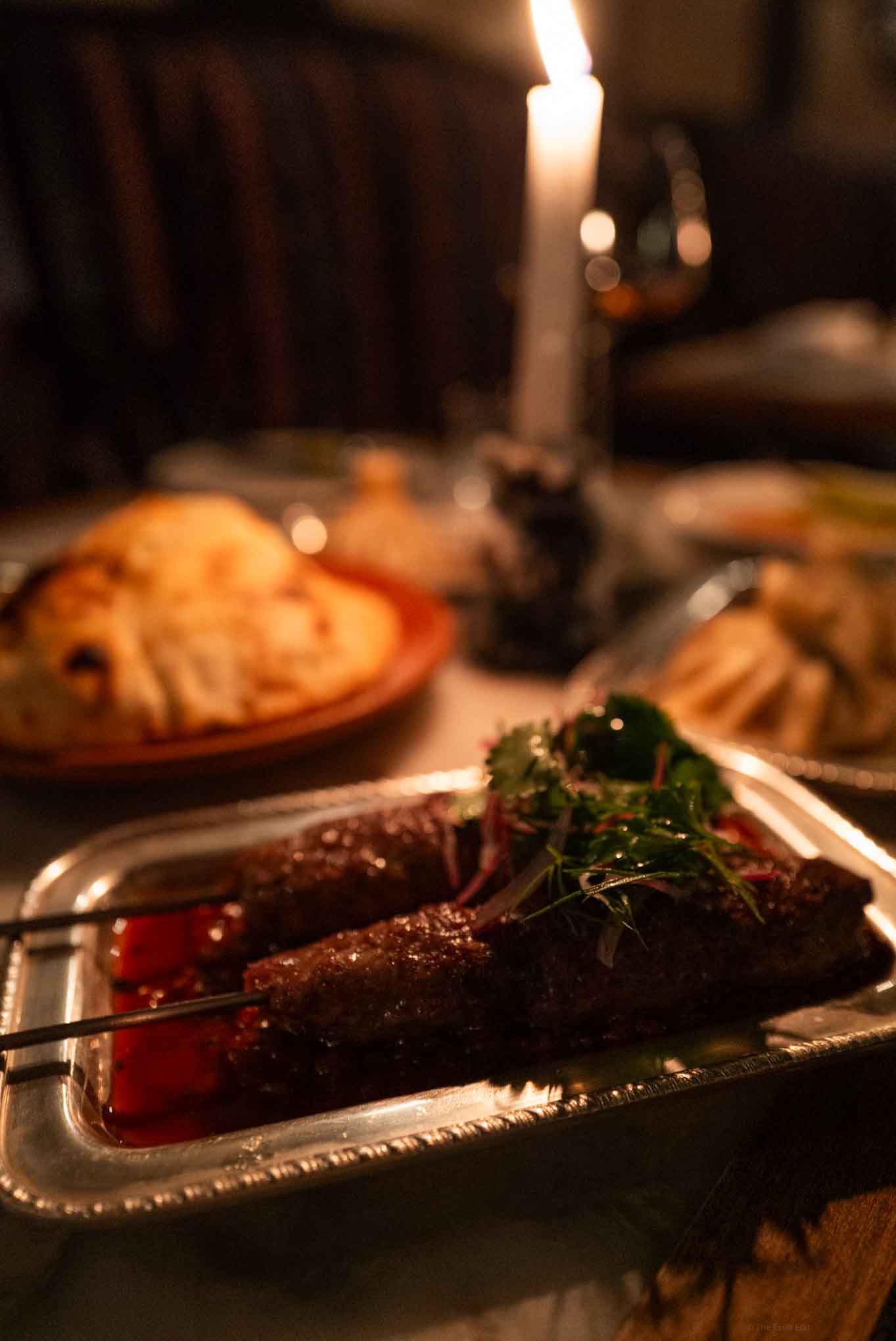 Gourmet beef skewers garnished with fresh herbs on a silver platter at Georgian London restaurant Daka Daka