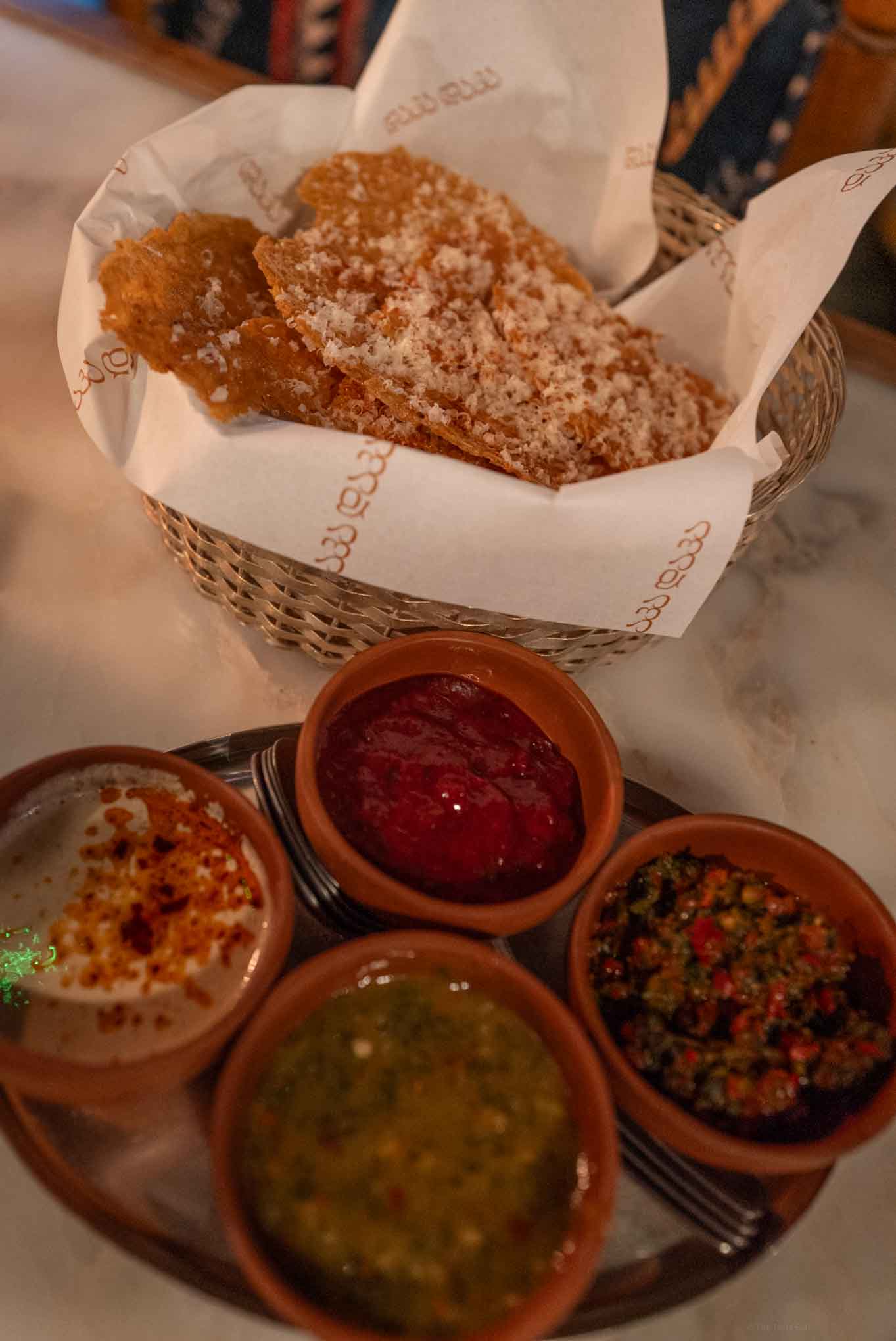 Crispy Georgian crackers served with colorful dipping sauces in small bowls.
