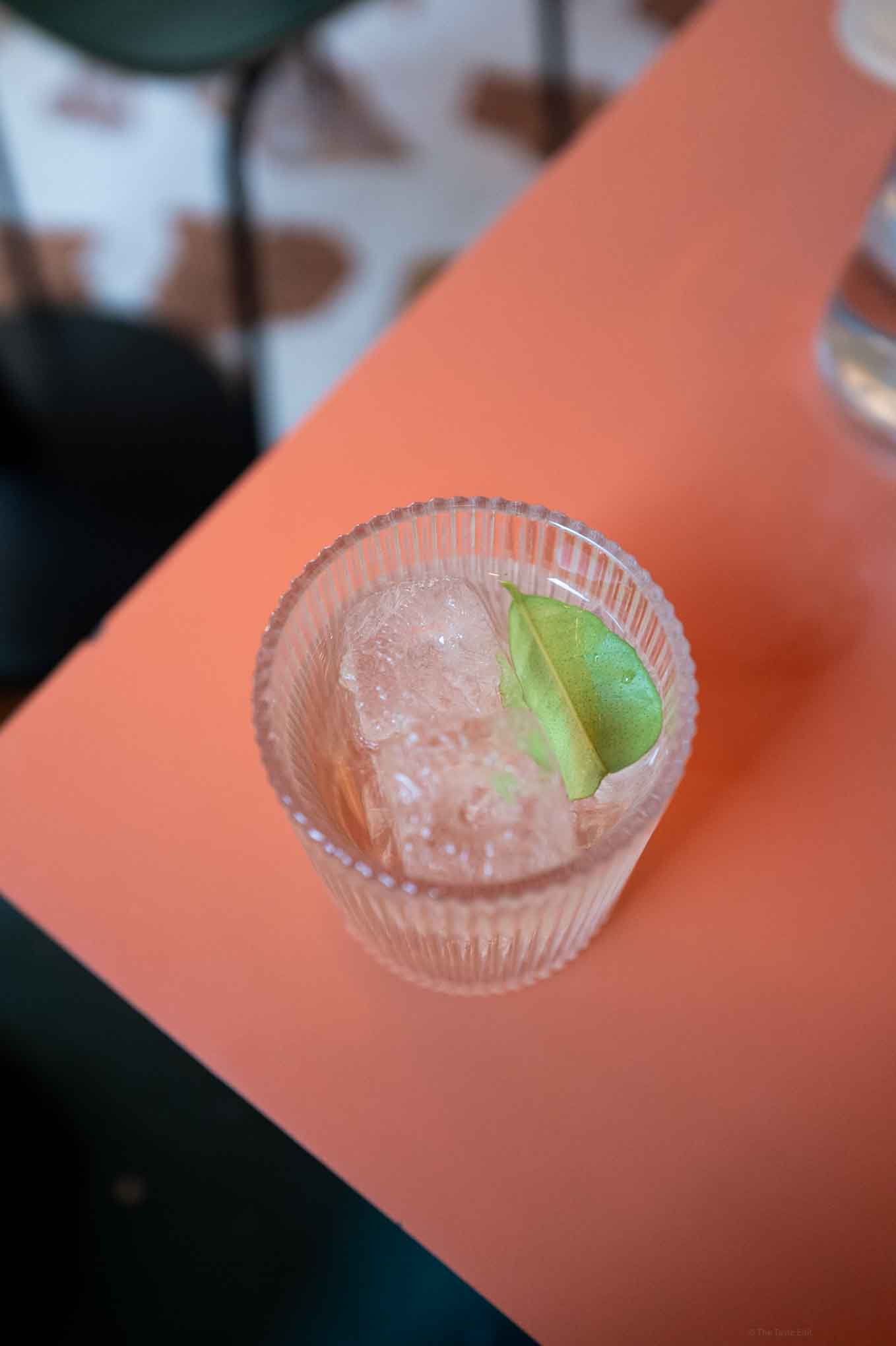 Refreshing citrus cocktail with ice and lime wedge in a clear glass at Singburi in London .