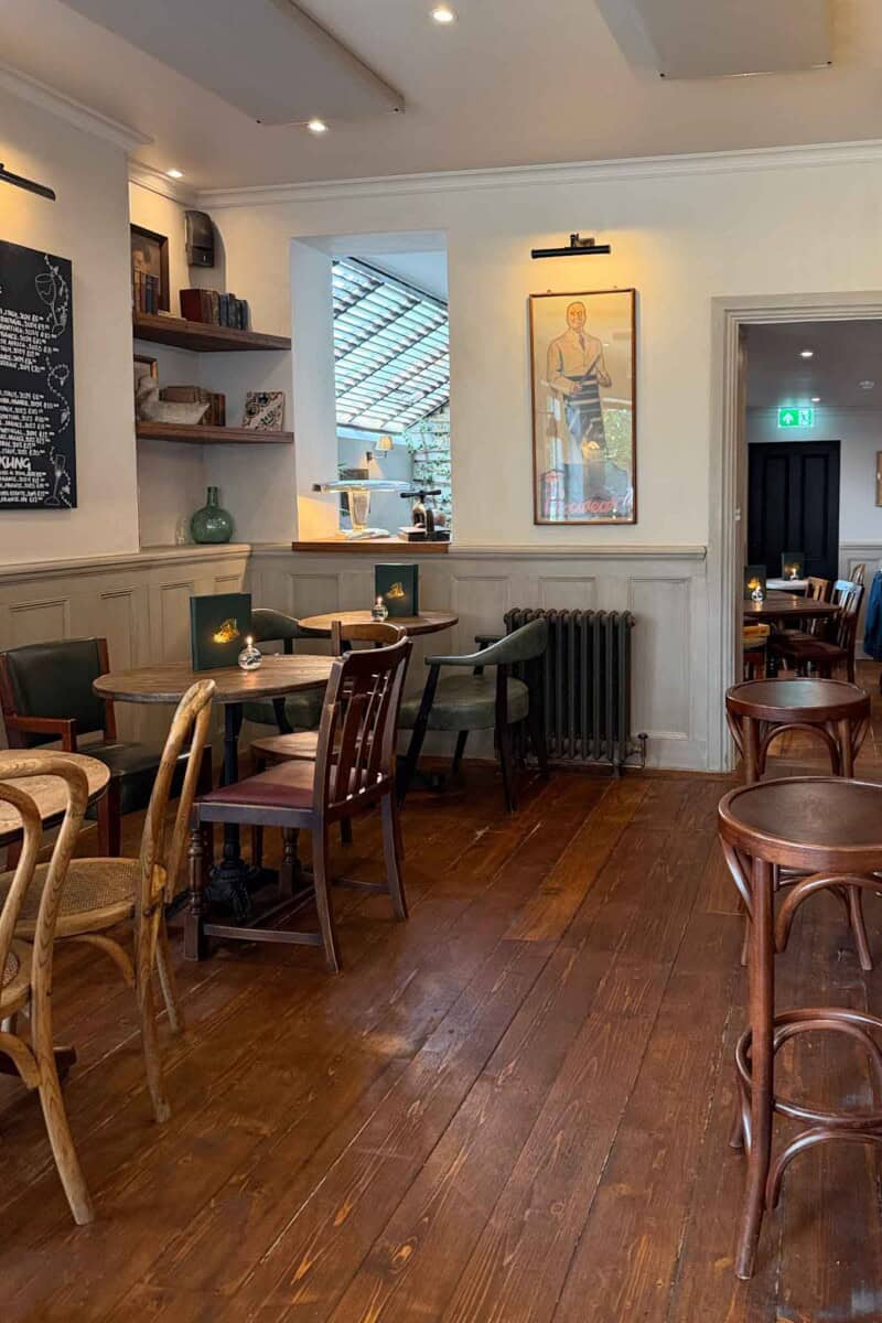 Inviting London pub interior with wooden tables, chairs, and artwork on white walls.