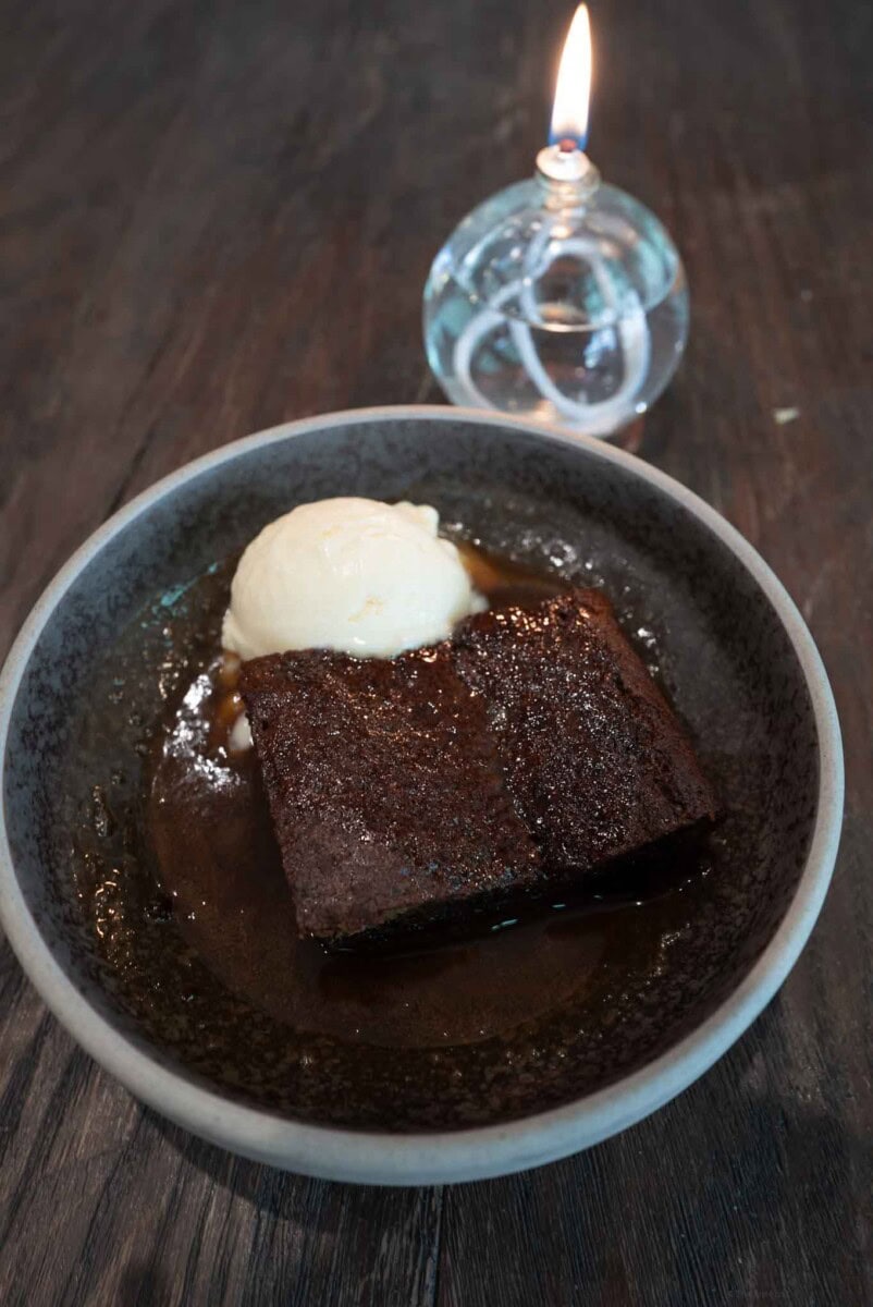 Delicious sticky toffee pudding cake served with vanilla ice cream, topped with a small candle for an elega.