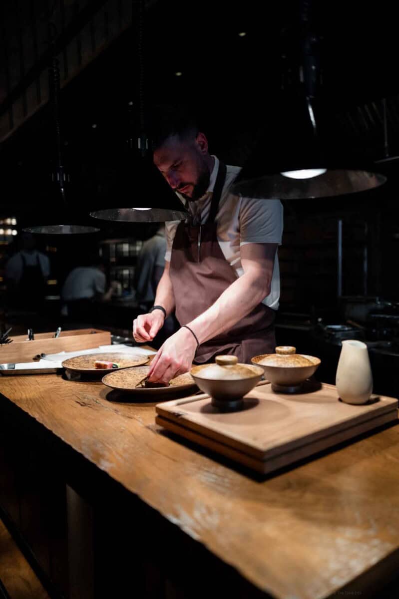 Chef preparing dishes in a contemporary kitchen setting for a culinary experience.