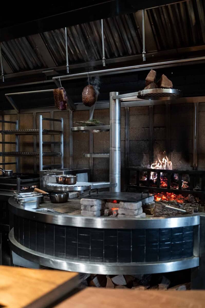 Wood-fired pizza oven with hanging herbs and cooking tools.