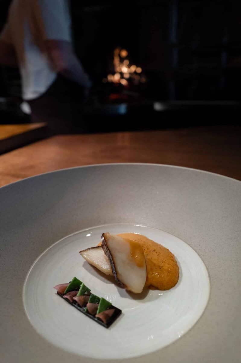 Delicious seafood dish featuring a piece of fish with sauce, served with a decorative garnish on a w.