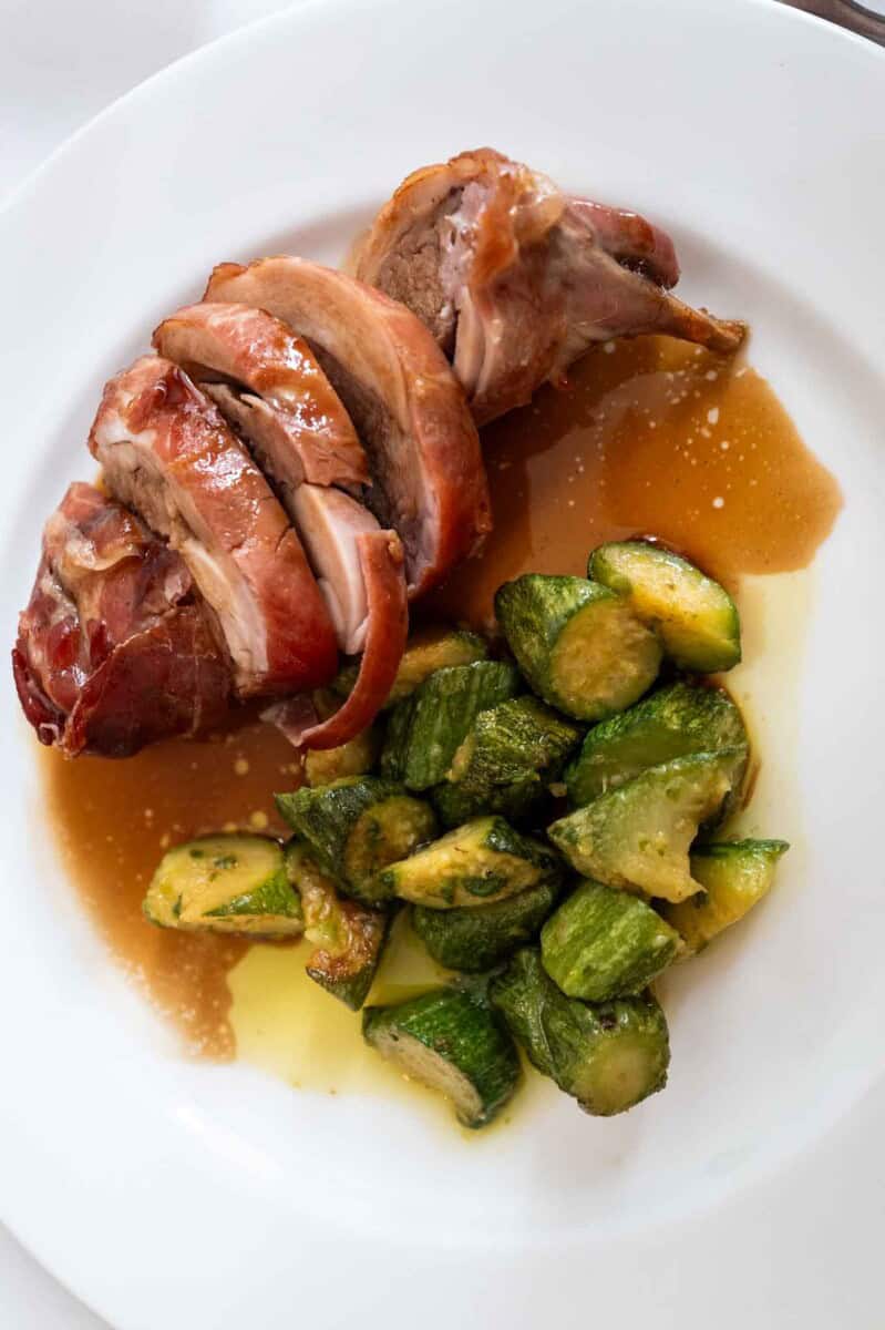 Roasted sliced rabbit porchetta at the lavery wrapped in PROSCHUTTO served with a side of chopped zucchini