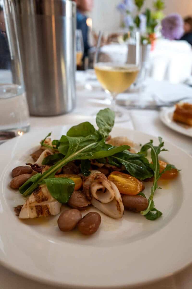 Seafood salad with beans and greens on a white plate at The Taste Edit.