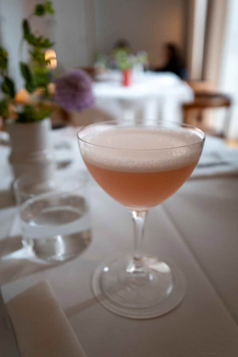 Elegant pink cocktail served in a coupe glass on a refined restaurant table.