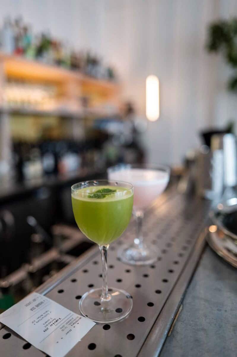 Refreshing green cocktail served in a cocktail glass at a modern bar setting.