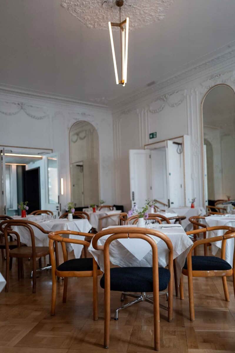 Stylish dining area featuring wooden chairs, white tablecloths, and sophisticated interior design.