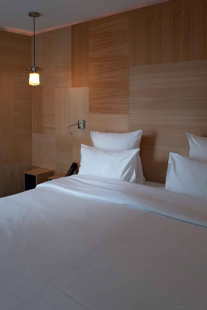 Comfortable hotel room featuring a cozy bed with white linens and a stylish wooden accent wall.