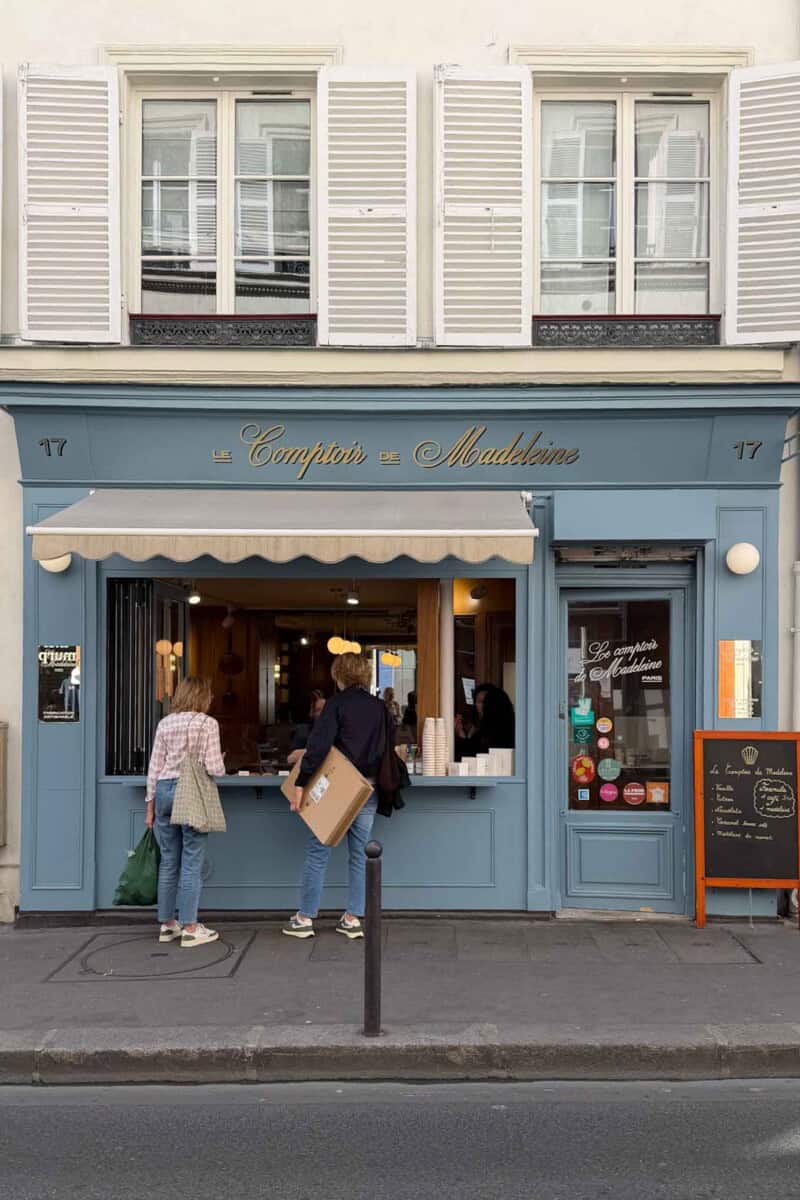 Charming Parisian café with blue façade, outdoor seating, and welcoming atmosphere.