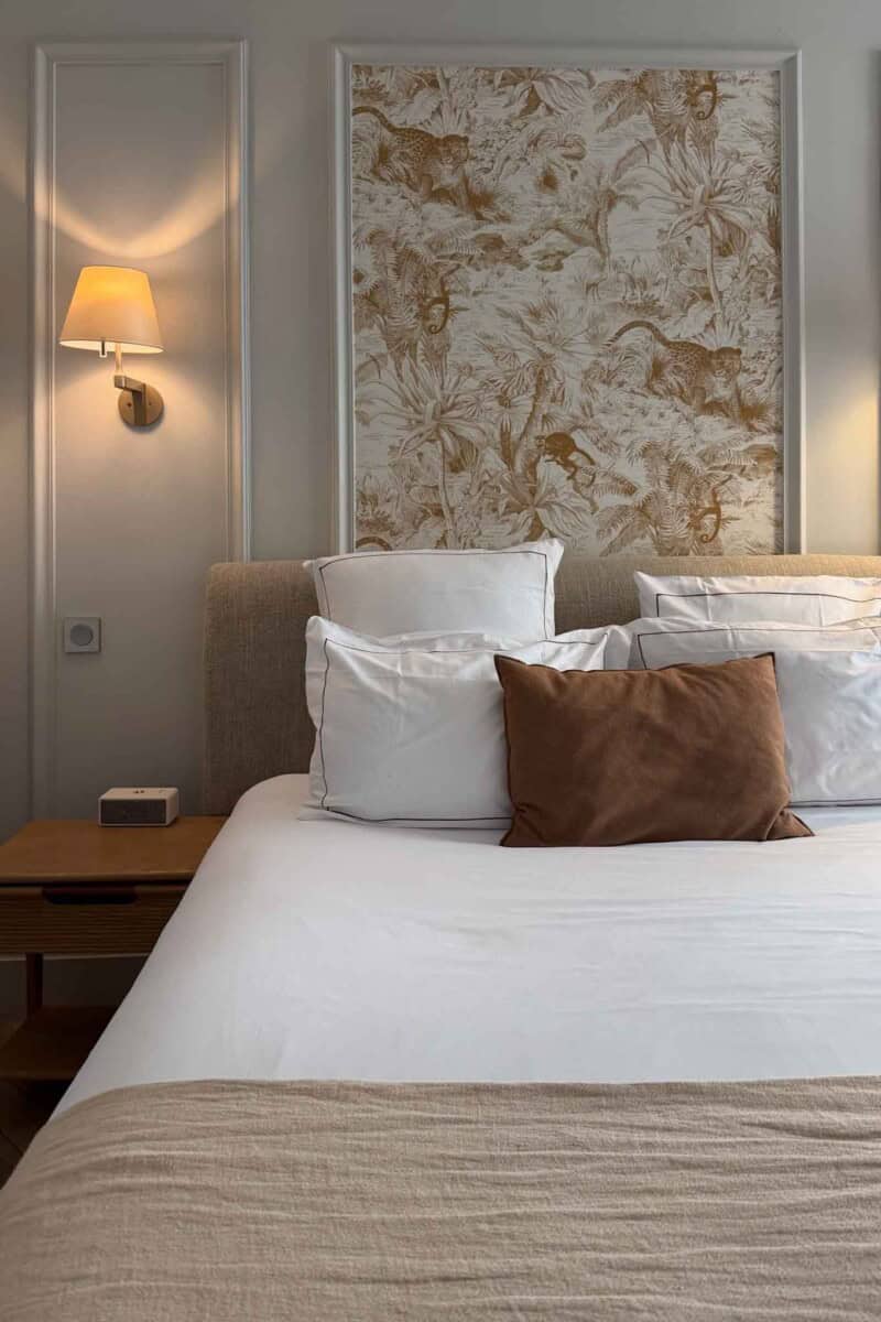 Cozy bedroom featuring a bed with white linens, brown accent pillow, and floral wall art.