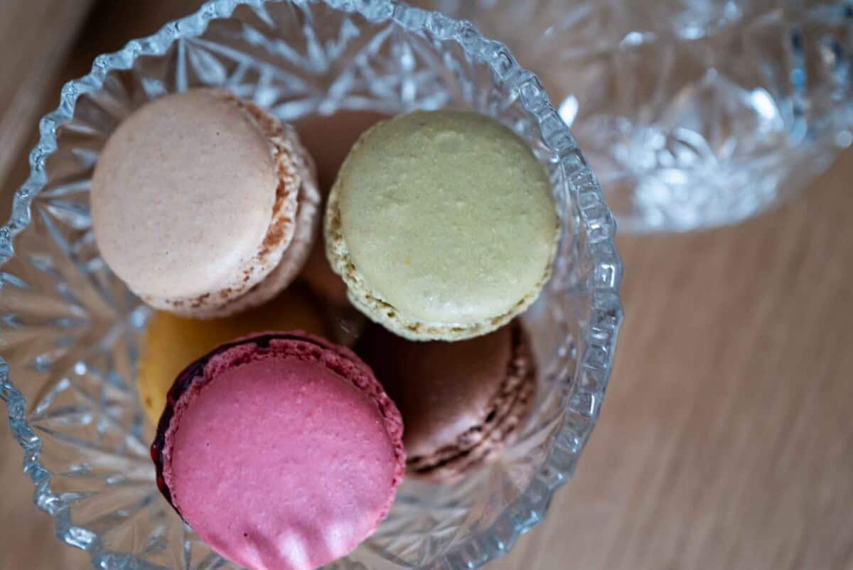 Colorful French macarons in a glass container for elegant dessert presentation.