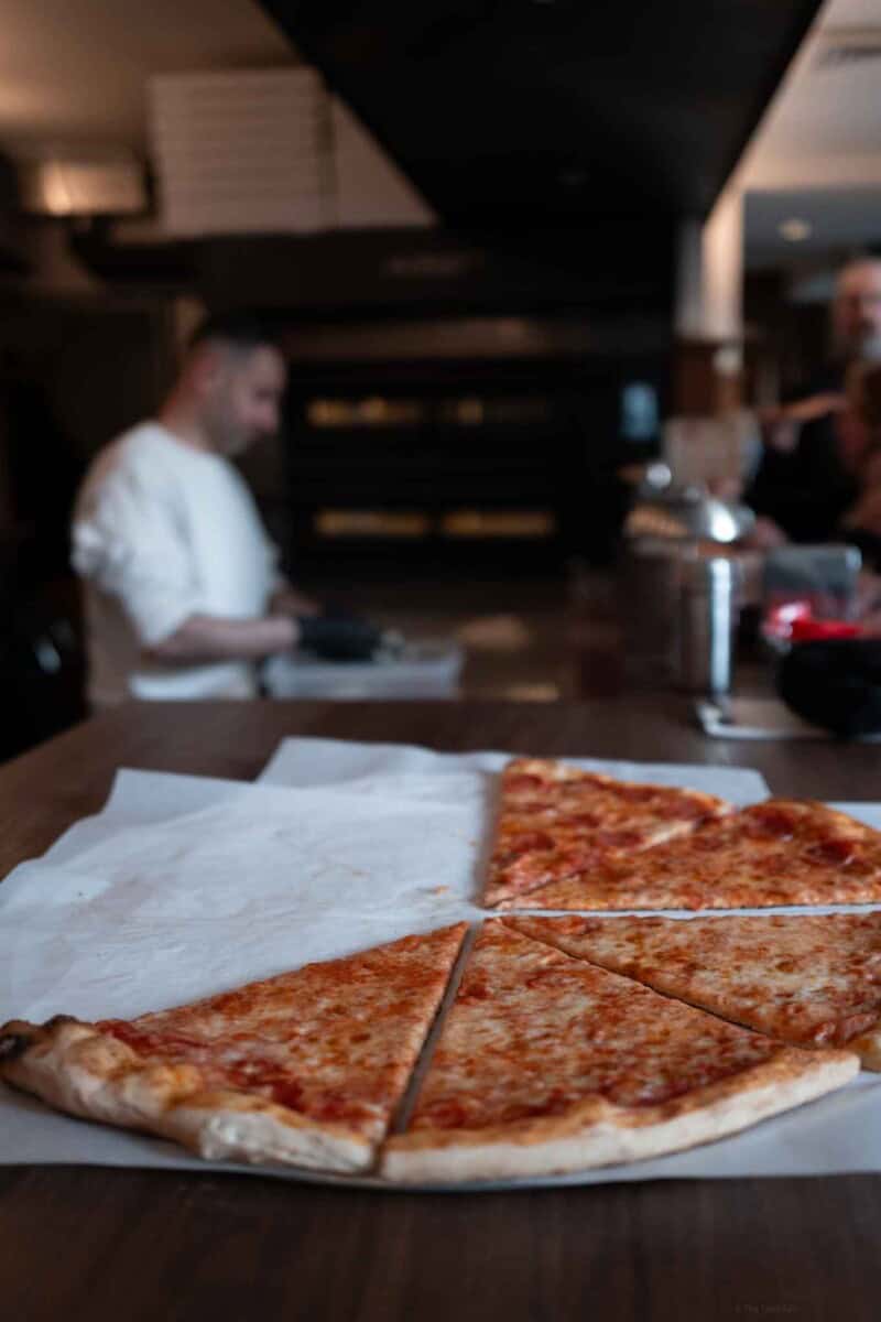 Pizza slices on parchment paper in a restaurant setting.