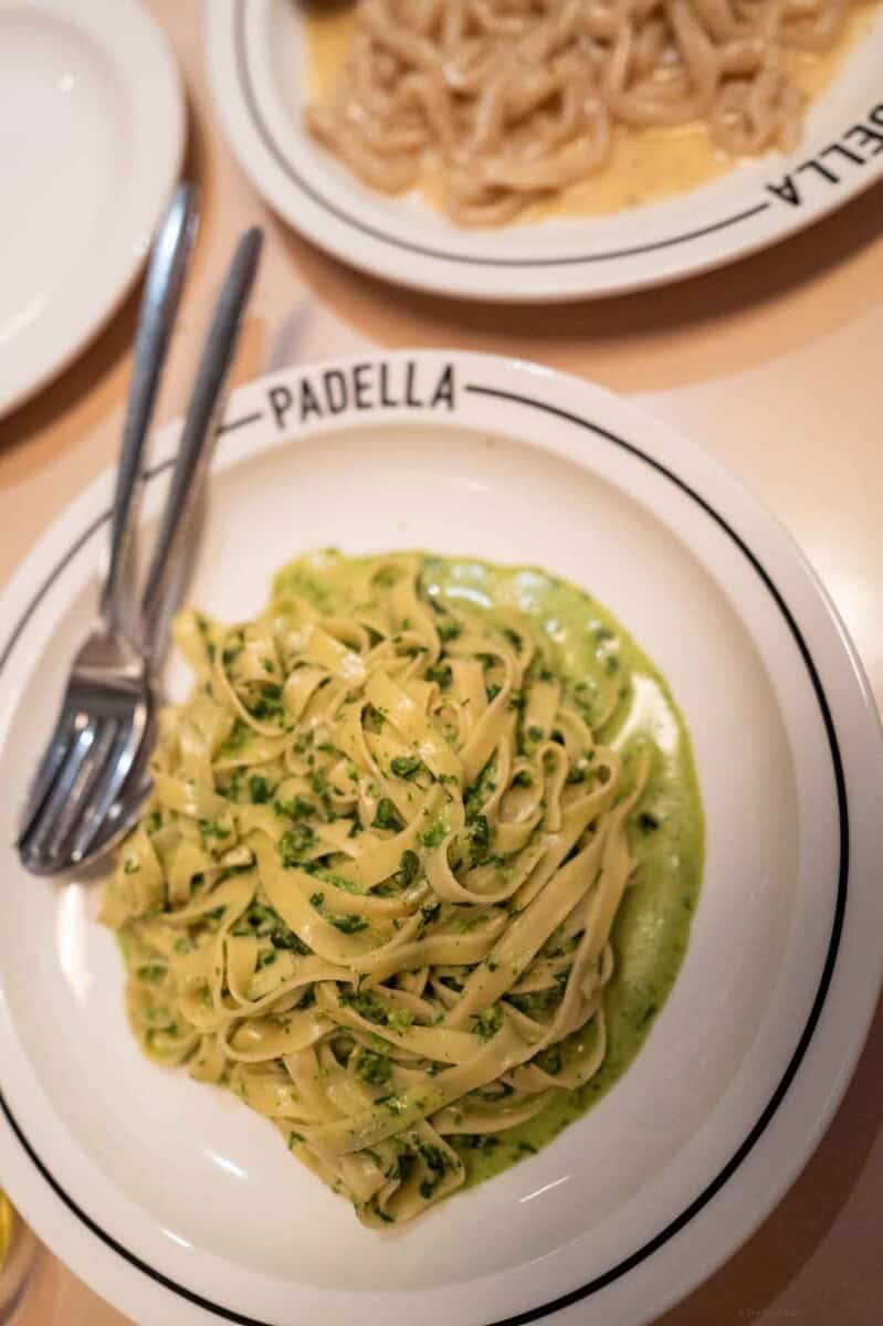 Fettuccine pasta with basil pesto sauce served in a white bowl at The Taste Edit.