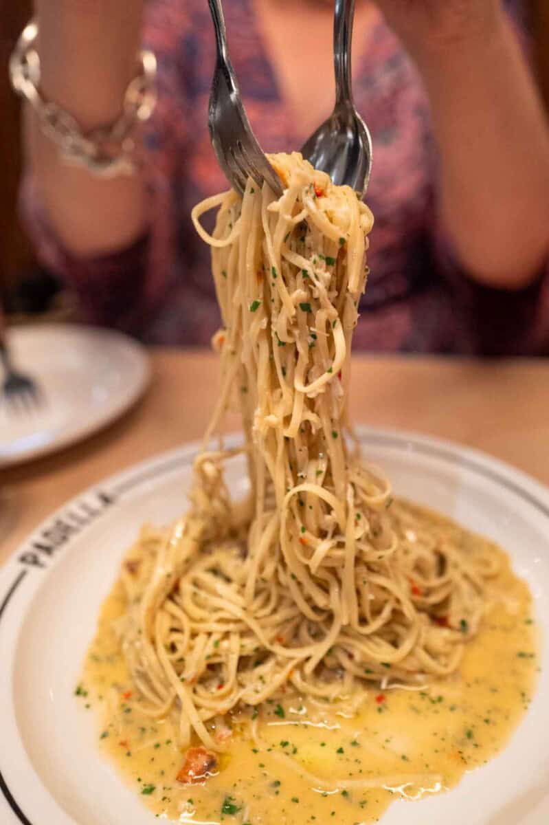 Delicious creamy pasta with herbs and vegetables, served on a white plate.