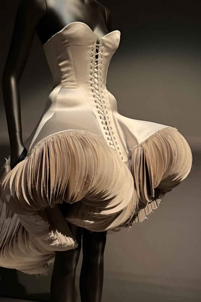 Schiaparelli Elegant beige corset dress with ruffled skirt and lace-up front, perfect for high fashion or runway.