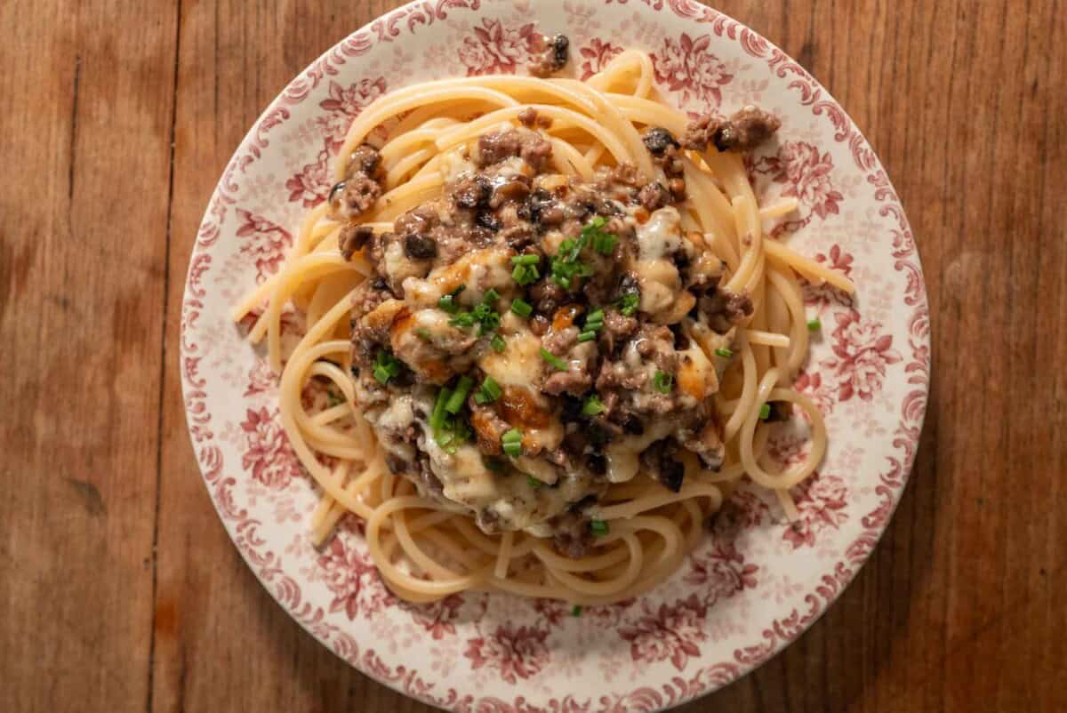 Delicious pasta with mushroom and cheese sauce, served on a floral plate. Perfect for a hearty staff.