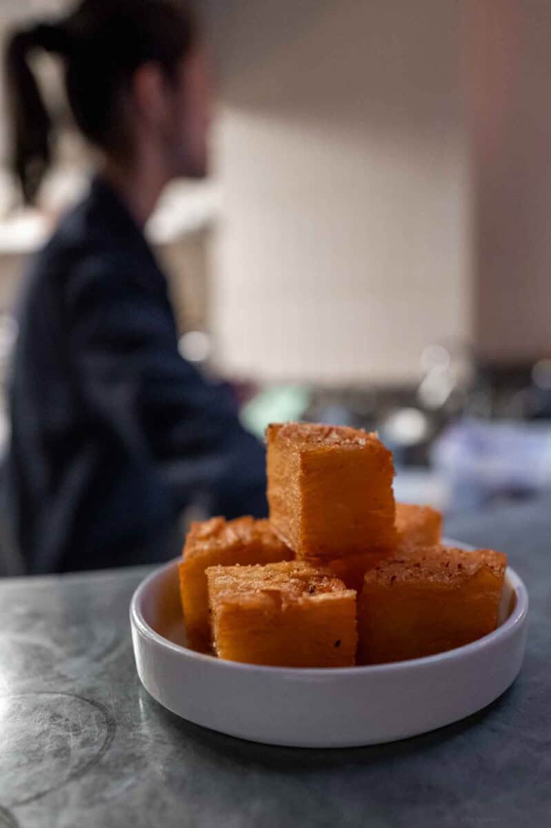 Delicious homemade caramel fudge squares in a white bowl on a kitchen counter.