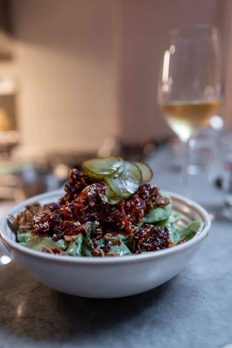 Asian beef salad with herbs, vegetables, and a tangy dressing in a white bowl.