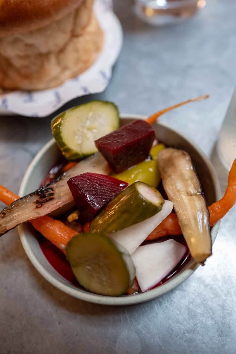 Assorted pickled vegetables including cucumbers, beets, carrots, and onions in a small bowl.