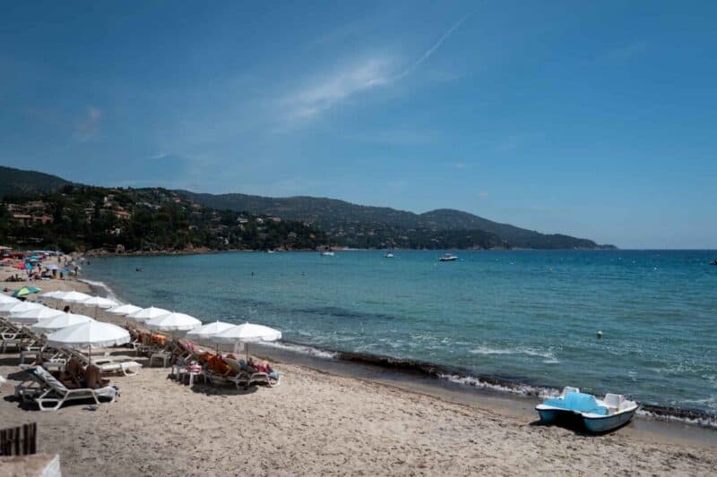 Beautiful beach scene with sunbeds, umbrellas, and boats on a sunny day.