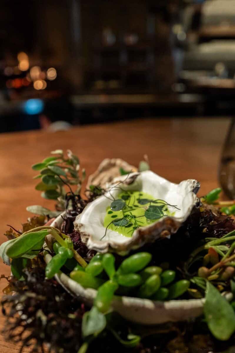 Seafood dish with fresh greens and edible flowers on a rustic plate.