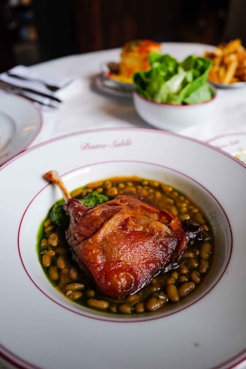 Crispy duck confit at a french bistro in London with bistro on a white tablecloth and fries and green salad at Bistro sable in canonbury